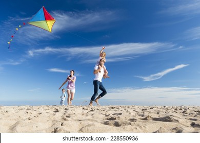 Family Enjoying a Day on the Beach Flying a Kite - Powered by Shutterstock