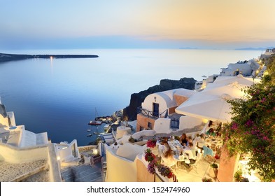 A Family Enjoying Dinner At A Restaurant In Santorini.