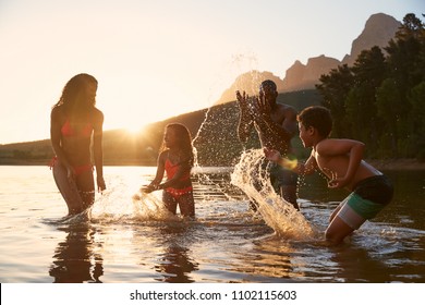 Family Enjoying Evening Swim In Countryside Lake