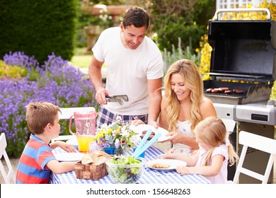 Family Enjoying Outdoor Barbeque In Garden