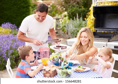 Family Enjoying Outdoor Barbeque In Garden