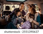 Family enjoying a road trip inside their car with kids taking photos and drinking from thermos