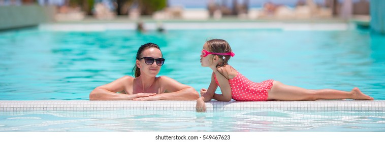 Family Enjoying Summer Vacation In Luxury Swimming Pool