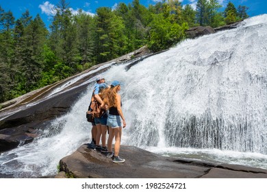 Family enjoying time together by the waterfall. People on hiking trip at High Falls of Dupont State Forest . Blue Ridge Mountains.  Cedar Mountain, North Carolina, USA