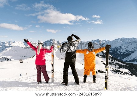 the family enjoys the mountain views before skiing back to the valley. skiing. family winter holiday. ski resort.