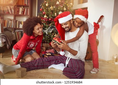 Family exchanging gifts in front of Christmas tree