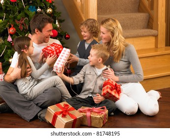 Family exchanging gifts in front of Christmas tree - Powered by Shutterstock