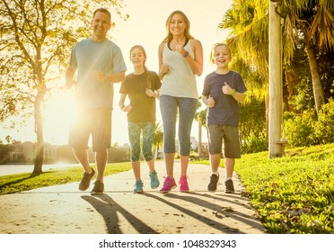 Family Exercising And Jogging Together At An Outdoor Park