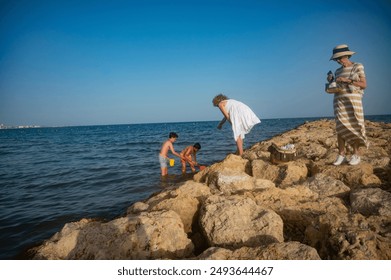 Family exploring rocky beach area on a sunny day - Powered by Shutterstock