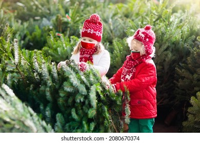 Family in face mask selecting Christmas tree. Safe Xmas shopping in covid-19 pandemic. Coronavirus prevention in winter holiday season. Kids choosing freshly cut tree at outdoor lot. 