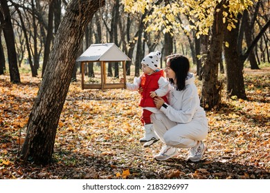 Family Fall Activities. Happy Family Mom And Toddler Baby Girl Feeding The Birds Outdoors In Fall Park.
