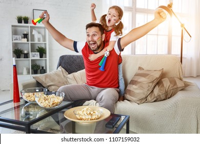 A Family Of Fans Watching A Football Match On TV At Home
