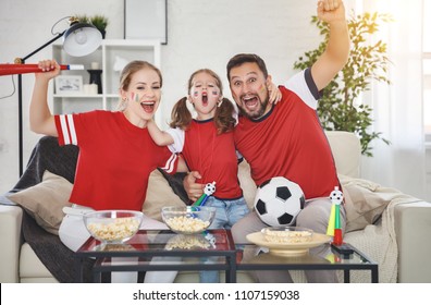 A Family Of Fans Watching A Football Match On TV At Home
