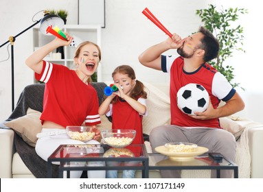 A Family Of Fans Watching A Football Match On TV At Home
