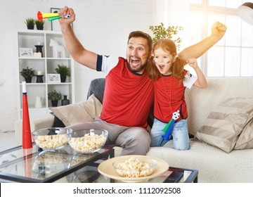 A Family Of Fans Watching A Football Match On TV At Home
