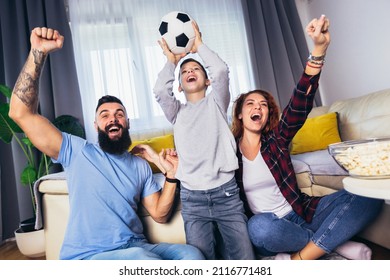 Family Of Fans Watching A Football Match On TV At Home