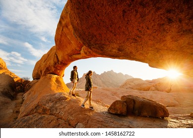 Tatăl și fiica familiei se bucură de răsărit în zona Spitzkoppe cu arcuri pitorești de piatră și formațiuni unice de rocă în Damaraland Namibia