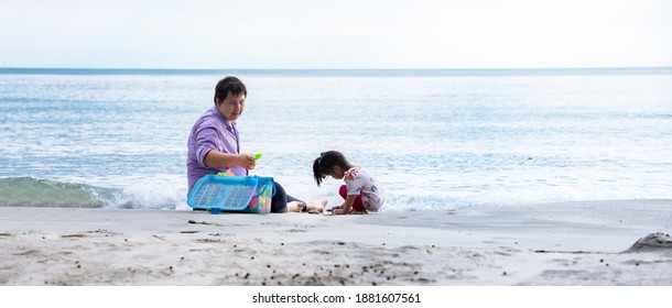 Family Of Father And Daughter Playing Toys In The Sand On The Beach. Children Play With Sand To Stimulate Their Senses. Building Relationship In The Family Concept.