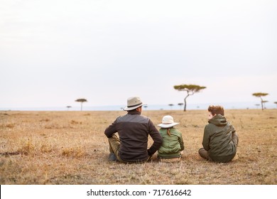 Family Of Father And Kids On African Safari Vacation Enjoying Views Over Masai Mara In Kenya