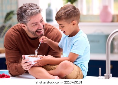 Family With Father In Kitchen With Son Sitting On Counter Eating Breakfast - Powered by Shutterstock