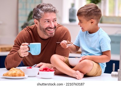 Family With Father In Kitchen With Son Sitting On Counter Eating Breakfast Together - Powered by Shutterstock