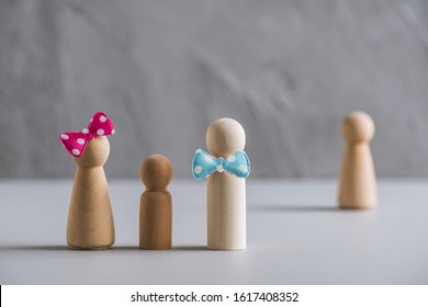 Family Father, Mother And Baby From Wooden Men In The Foreground. Woman Surrogate Mother Behind Them. Surrogacy Concept.