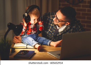 Family Father And Son Baby Listening To Music With Headphones In The Dark Night
