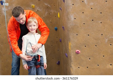 Family Of Father And Son Ready For Rock Climbing In Indoor Gym