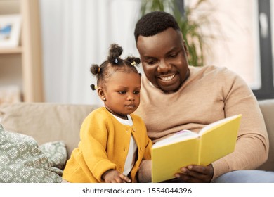 Family, Fatherhood And People Concept - Happy African American Father Reading Book For Baby Daughter At Home