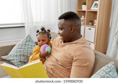 Family, Fatherhood And People Concept - Happy African American Father Reading Book For Baby Daughter At Home