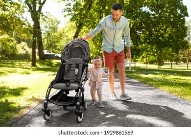 family, fatherhood and people concept - happy father with child in stroller walking at summer park