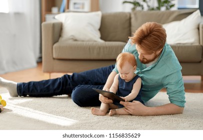 family, fatherhood and technology concept - happy red haired father and little baby daughter with tablet pc computer at home - Shutterstock ID 1156835629