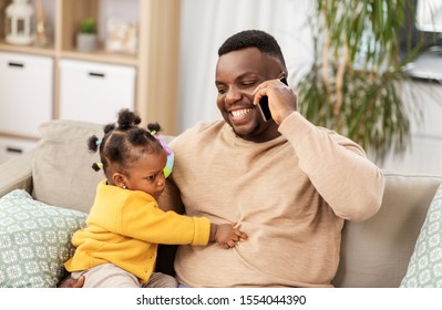 family, fatherhood and technology concept - happy african american father with baby at home calling on smartphone - Powered by Shutterstock