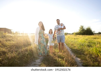 Familie auf dem Feld, die bei Sonnenuntergang geht