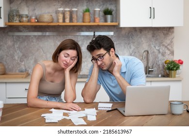 Family Financial Crisis Concept. Shocked And Stressed Couple Counting Expenses, Taxes And Debts. Laptop And Many Bills On The Table