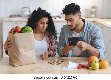 Family Financial Crisis Concept. Upset Arab Spouses Counting Remaining Money After Shopping, Young Middle Eastern Couple Shocked About Big Prices For Grocery, Looking At Empty Wallet At Home