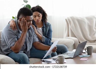 Family Financial Crisis. Depressed Black Couple Sitting With Huge Bills In Living Room, Counting Spends, Don't Have Money To Pay Credit