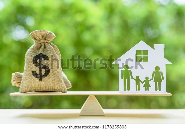 Family financial management, mortgage and\
payday loan or cash advance concept : Dollar bags, 4 members family\
under a house or shelter on a balance scale, depicts short term\
borrowing for a\
residence.