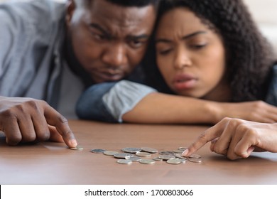 Family Financial Problems. Young Black Couple Counting Remaining Coins On Table, Suffering From Poverty And Absence Of Money, Selective Focus