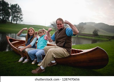 Family Flexing Muscles Sitting On Canoe