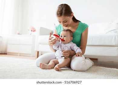 Family, Food, Child, Eating And Parenthood Concept - Mother With Puree And Spoon Feeding Little Baby At Home