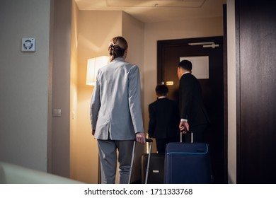 A Family In Formal Wear Leaving A Hotel Room With Their Suitcases