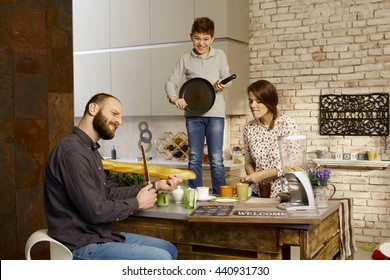 Family Forming A Band In Kitchen, Pretending To Play On Instruments.