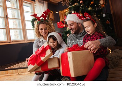 Family of four celebrating Christmas, exchanging presents  