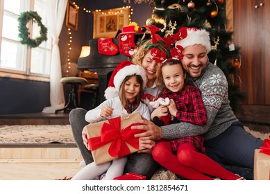 Family of four celebrating Christmas, exchanging presents  