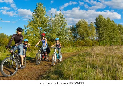 Family Of Four Cycling Outdoors. Happy Parents With Two Kids On Bikes