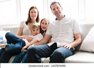 Family of four having fun on the sofa at home - Shutterstock ID 1107874490