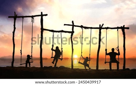 Family of four having fun on rope swing at the beach during sunset