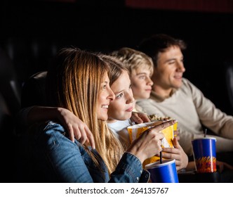 Family Of Four Having Snacks While Watching Movie In Cinema Theater