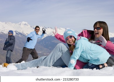 Family Of Four Having Snow Ball Fight In Snow Field, Smiling, Mountain Range In Background